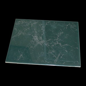May include: A green ceramic tile with a white marbled pattern. The tile has a smooth, glossy finish.