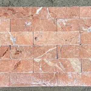 May include: A close-up of a red marble tile wall panel. The tiles are arranged in a brick pattern and have a natural, rustic look.
