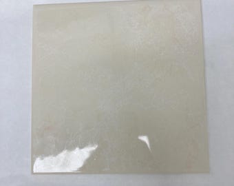 Baldosa cuadrada de cerámica color crema con efecto mármol brillante de 6x6 cm, marca Laufen (muestra).