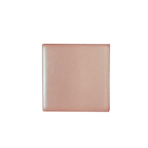 May include: A single, square, light pink tile with a slightly textured surface.