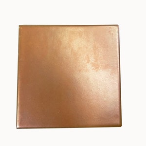 May include: A square tile with a smooth, metallic finish in a warm copper color.