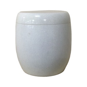 May include: A white ceramic urn with a smooth, rounded shape. The urn has a lid and is made of a speckled material.