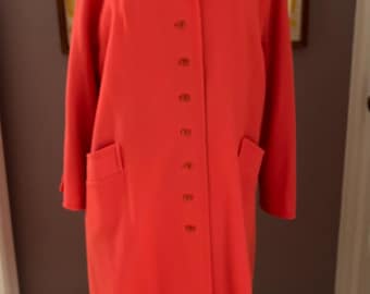 May include: A long, bright orange coat with a button-up front and two pockets. The coat is made of a smooth fabric and has a classic, tailored look.