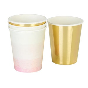 May include: A set of disposable paper cups, one gold and one with a pink ombre design. The cups are perfect for parties or special occasions.