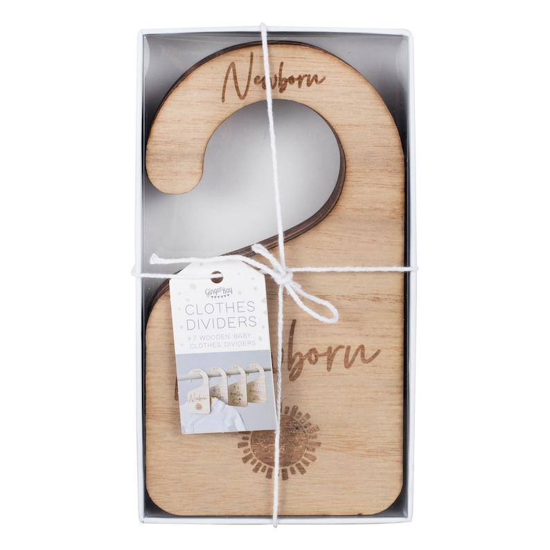 May include: A set of seven wooden baby clothes dividers in a clear plastic box. The dividers are engraved with the word "Newborn" and a sun design. The box is tied with a white ribbon.