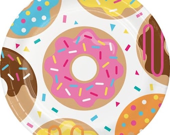 May include: White paper party plates with a donut theme. The plates feature colorful donuts with sprinkles and different colored icings.