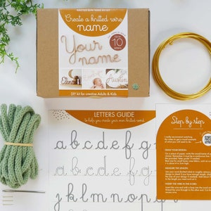May include: A craft kit for making knitted wire names. The kit includes a cardboard box with the text "Create a knitted wire name", a spool of gold wire, a bundle of green yarn, and instructions. The kit is designed for adults and kids.