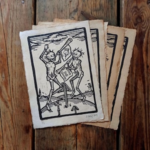 Könnte beinhalten: Ein Schwarz-Weiß-Holzschnitt mit zwei Skeletten, die Musikinstrumente spielen. Die Skelette stehen auf einem Hügel mit einem Wegweiser, der nach oben zeigt. Der Druck ist signiert und datiert mit "S. Lucid 2023".