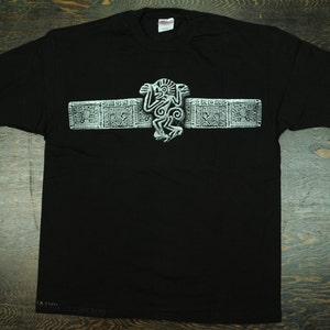 May include: Black t-shirt with a white graphic of a stylized monkey and geometric designs. The design is reminiscent of ancient Mayan art.