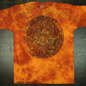 May include: Orange tie-dye t-shirt with a black print of the Aztec calendar. The shirt has a faded, vintage look and says "Nappy Threads" at the bottom.