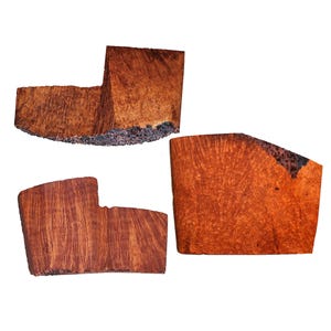 May include: Three distinct pieces of raw, reddish-brown wood burl with visible grain patterns and natural, dark, textured bark edges. Each piece features a unique, irregular shape with smooth, flat surfaces showcasing the intricate wood grain.