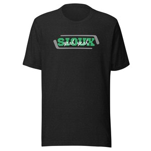 May include: Black t-shirt with a green and white graphic that says "Sioux yeah yeah" in a retro font.