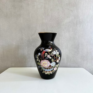 Könnte beinhalten: Schwarze Keramikvase mit goldfarbenem Rand und einem Blumendesign mit einem Vogel und Blumen in Rosa-, Blau- und Gelbtönen.