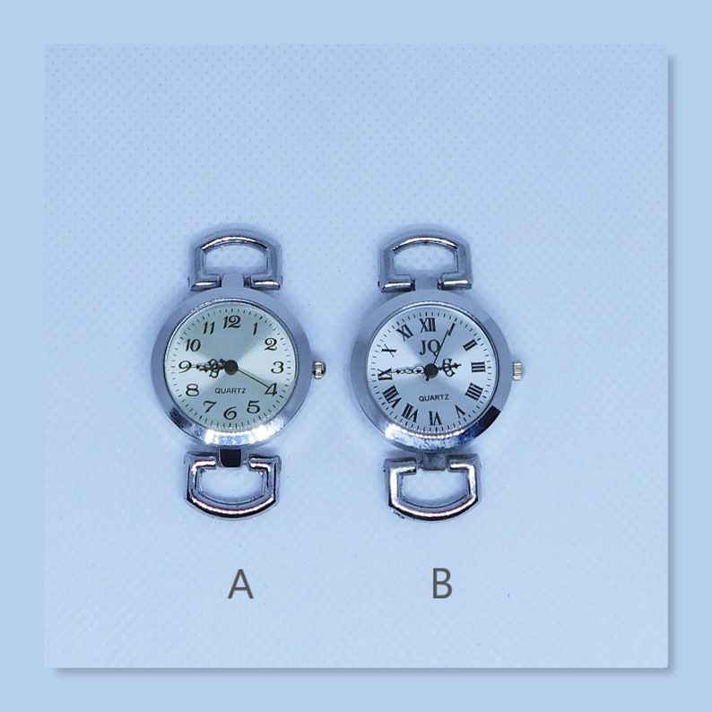 May include: Two silver-toned quartz watch faces with different dial designs. Watch A has Arabic numerals, while Watch B features Roman numerals. Both have silver bands and are labeled "QUARTZ".