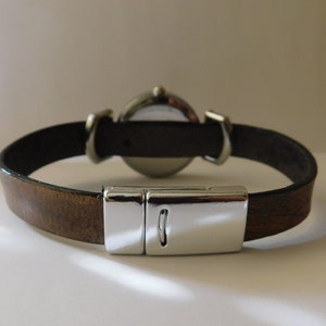 May include: A brown leather watch band with a silver clasp and a round watch face.