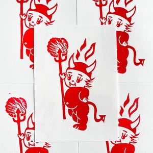 May include: Red devil print on white paper. The devil figure is holding a pitchfork and has a tail and horns. The image is repeated multiple times on a white background.
