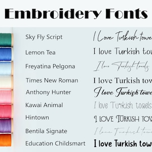 May include: A collection of embroidery fonts displayed on a white background with a row of colored thread spools on the left side. The fonts are shown in different styles and sizes, including cursive, script, and block lettering. The text reads "I Love Turkish Towels" in various styles.