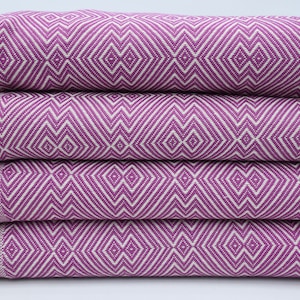 May include: A stack of four purple and white patterned towels with fringe edges.