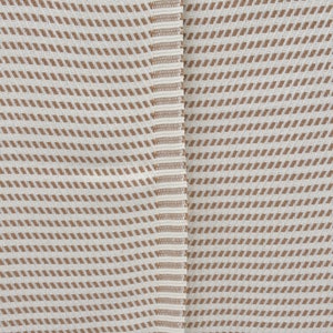 K&ouml;nnte beinhalten: Nahaufnahme eines wei&szlig;en Stoffes mit braunem diagonalem Streifenmuster. Der Stoff hat eine subtile Textur und ein leicht raues Gef&uuml;hl.