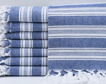 May include: A stack of blue and white striped towels with white fringe. The towels are folded and stacked on a white surface.