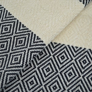 May include: A black and white patterned fabric with a diamond design. The fabric is woven with a textured surface.
