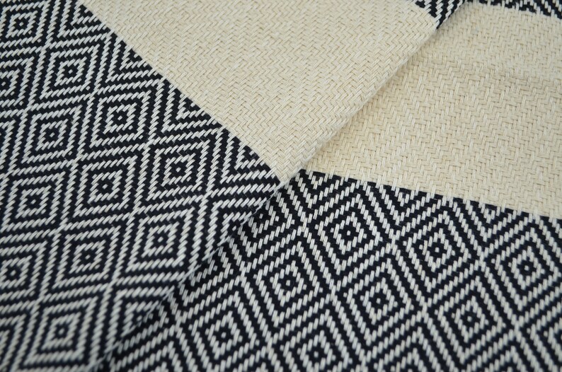 May include: A black and white patterned fabric with a diamond design. The fabric is woven with a textured surface.