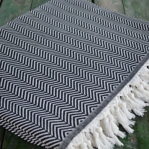 May include: Black and white chevron patterned throw blanket with white fringe.