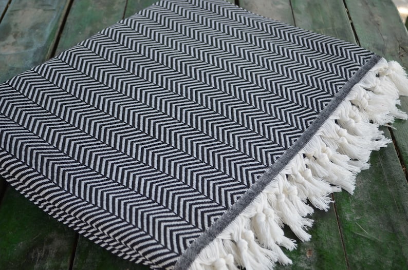 May include: Black and white chevron patterned throw blanket with white fringe.