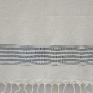 May include: A white cotton kitchen towel with a black striped border and fringe.