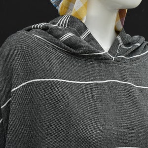 May include: A black and white striped hooded towel with a short sleeve. The towel is made of a soft, absorbent material.