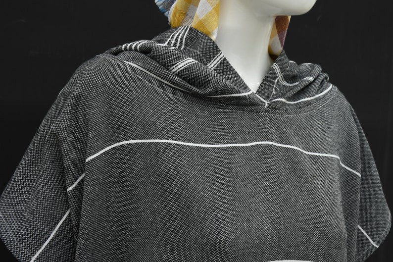 May include: A black and white striped hooded towel with a short sleeve. The towel is made of a soft, absorbent material.