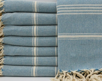 May include: A stack of blue and white striped towels with fringe edges. The towels are made of cotton and are soft and absorbent.
