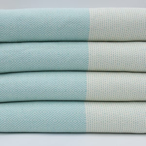 May include: A stack of four light blue and white patterned towels with fringe edges.