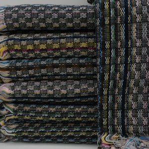 May include: A stack of black and white patterned towels with colorful fringe. The towels are made of a soft, absorbent material and are perfect for drying off after a swim or shower.