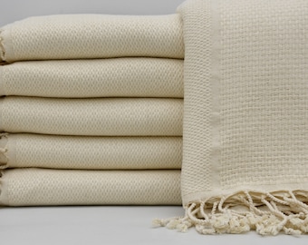 May include: A stack of six cream-colored towels with fringe edges. The towels are made of a soft, absorbent material and are perfect for drying off after a bath or shower.