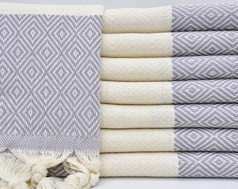 May include: A stack of six gray and white patterned Turkish towels with fringe. The towels are made of cotton and have a diamond pattern.
