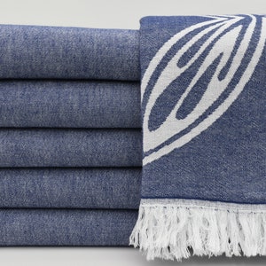 May include: A stack of six blue and white patterned towels with white fringe. The towels have a floral design.