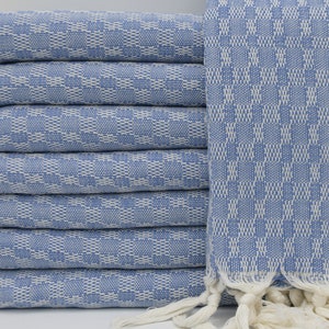 May include: A stack of blue and white patterned Turkish towels with fringed edges.