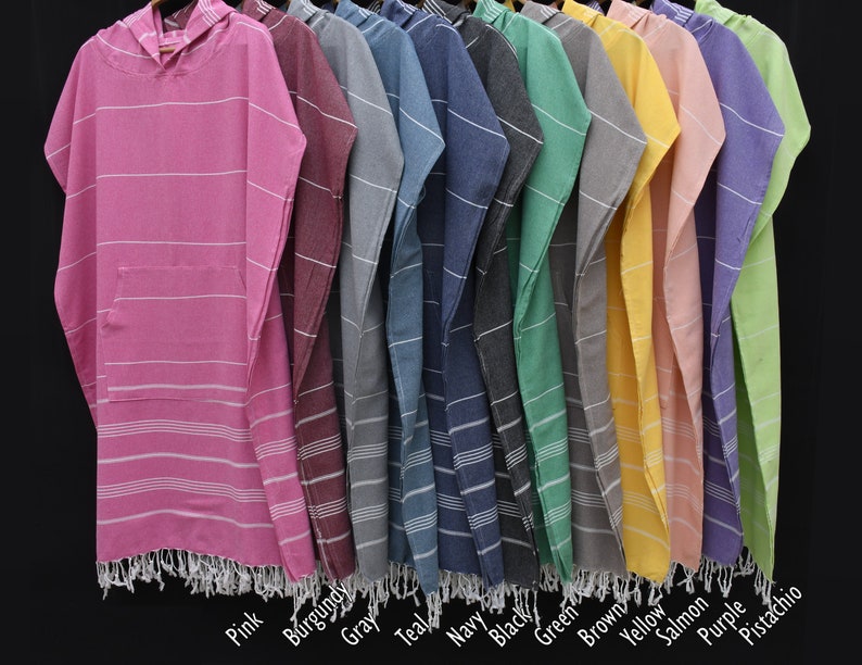 May include: A row of ten hooded towels in various colors, including pink, burgundy, gray, teal, navy, black, green, brown, yellow, salmon, purple, and pistachio. The towels have a striped pattern and fringe trim.
