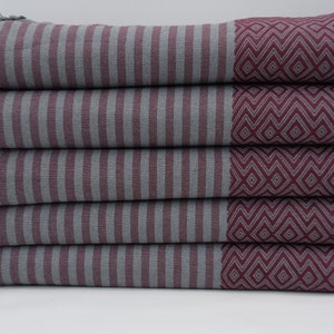 May include: A stack of five gray and burgundy striped towels with a geometric pattern on one side. The towels have a fringe on the edges.