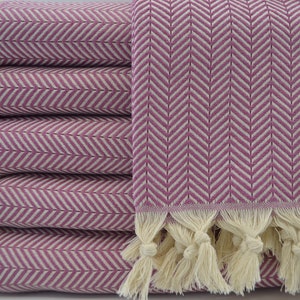 May include: A stack of pink and white patterned towels with fringe. The towels are folded and stacked on top of each other.