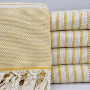 May include: A stack of yellow and white striped towels with a fringed edge. The towels are made of a soft, absorbent material and are perfect for drying off after a bath or shower.