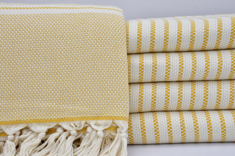 May include: A stack of yellow and white striped towels with a fringed edge. The towels are made of a soft, absorbent material and are perfect for drying off after a bath or shower.