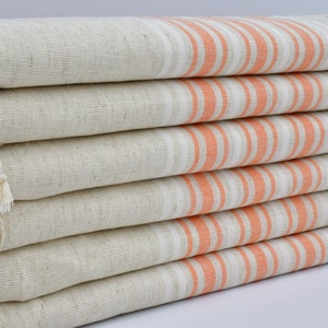 Può includere: Un mucchio di sei asciugamani color crema con strisce arancioni. Gli asciugamani hanno una frangia su un lato.