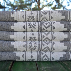 May include: A stack of five gray and white patterned towels with fringe edges. The towels have a geometric design with black and white accents.
