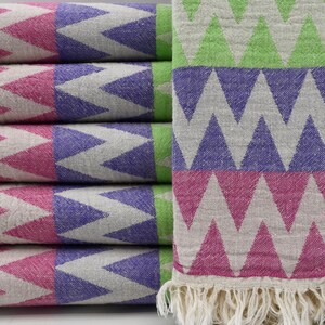 May include: A stack of pink, purple, and green patterned towels with white fringe. The towels have a chevron pattern.
