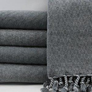 May include: A stack of gray Turkish towels with fringed edges. The towels are made of a soft, absorbent cotton and are perfect for drying off after a bath or shower.