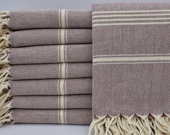 May include: A stack of eight burgundy Turkish towels with white stripes and white fringe.