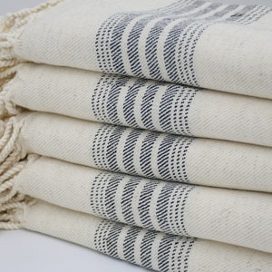 May include: A stack of five white towels with blue stripes. The towels have a fringe border.