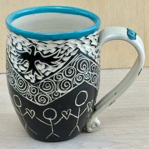 May include: A black ceramic mug with a white rim and handle. The mug is decorated with a white bird design, white swirls, and stick figures holding hearts. The mug is approximately 4 inches tall.